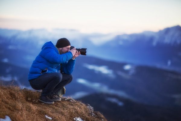 Man Taking Photos Standing On Mountain